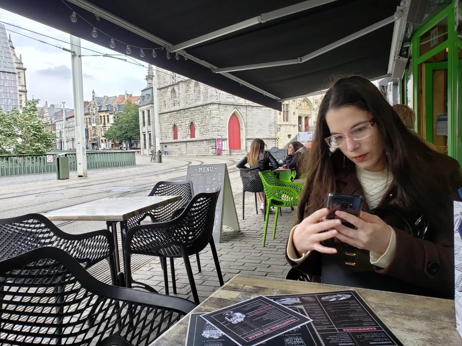 Laís sentada em um café ao ar livre em Ghent, Bélgica, numa tarde comum