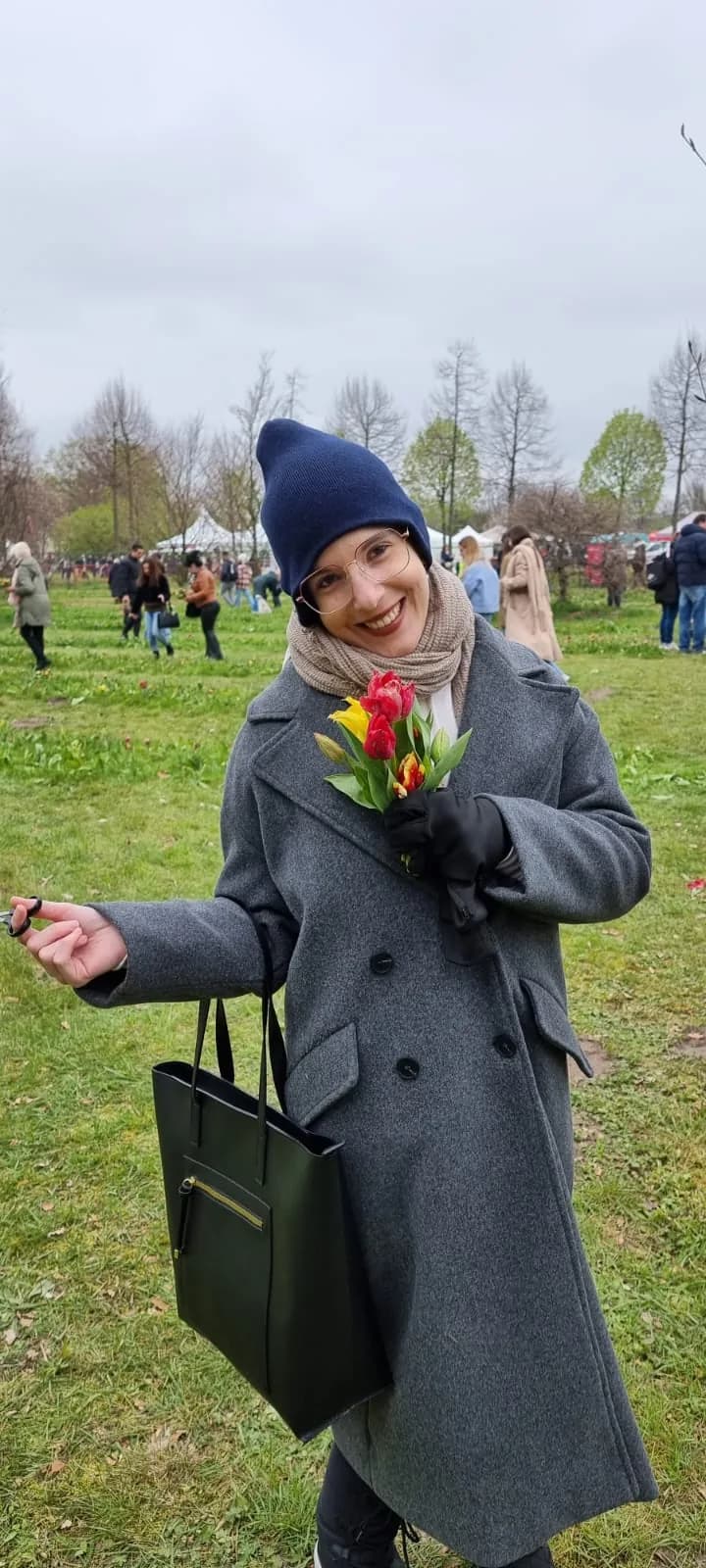 Laís em um campo de tulipas na primavera, segurando um pequeno buquê
